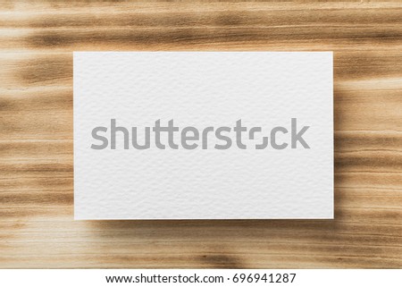 Closeup mockup of white blank horizontal business card at natural wooden background.