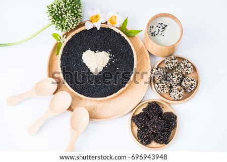 The black and white sesame in the wooden dish, soy milk containing black sesame in the wooden cup and cookies making from sesame nearly place, healthy food concept , selective focus photograph.