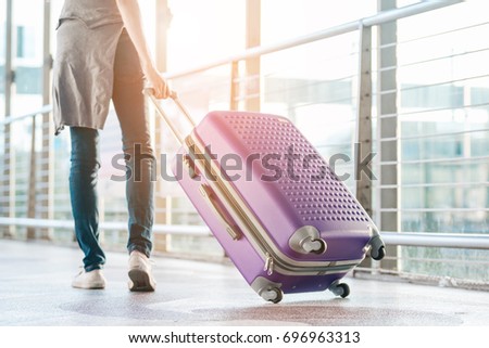 Asian teenage girl carrying a suitcase and walking along the access terminal for the airport early in the morning. Royalty-Free Stock Photo #696963313