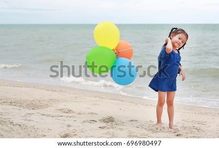 Adorable asian girl playing balloons on the beach
