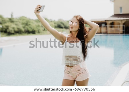 Portrait of beautiful girl taking a selfie at the swimming pool.