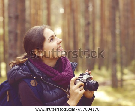 Young, beautiful and happy woman walking in forest and taking pictures. Camp, adventure, trip, hiking concept.