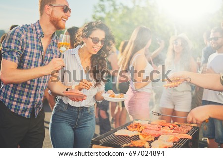     Small group of friends drinking alcohol and having a meal at barbecue party  Royalty-Free Stock Photo #697024894