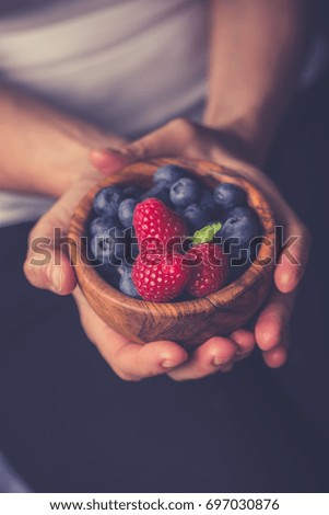 Young Woman with a bowl of fresh berries. Healthy breakfast.