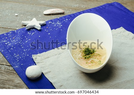 Clear soup with salmon and onion in a bowl on wooden background
