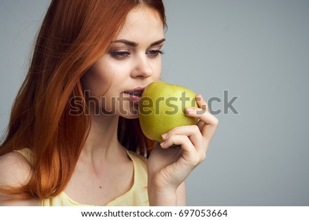 Woman with a green apple on a gray background, eating properly                               