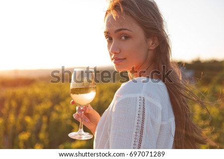 Portrait of young brunette beauty in the vineyards having wine.