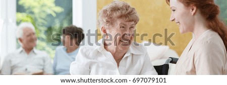 Happy senior woman talking with friendly nurse at geriatric ward Royalty-Free Stock Photo #697079101