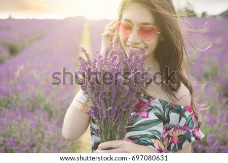 Smiling gentle young beautiful girl among the flowers of blooming lavender. Happy summer leisure walking.  