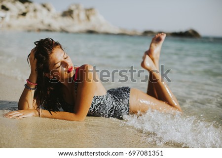 Pretty young woman lying in the water on the beach at sunny day