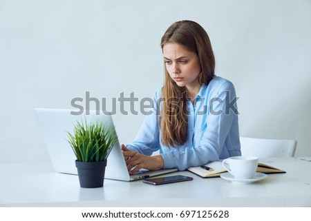 Business woman in a blue shirt prints on a laptop, office work                               
