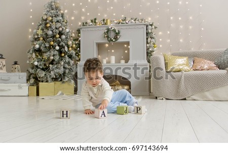 Cute toddler playing with his present in the decorated room. wooden toy. Family Xmas morning in decorated living room with kids gifts, fireplace Christmas tree.