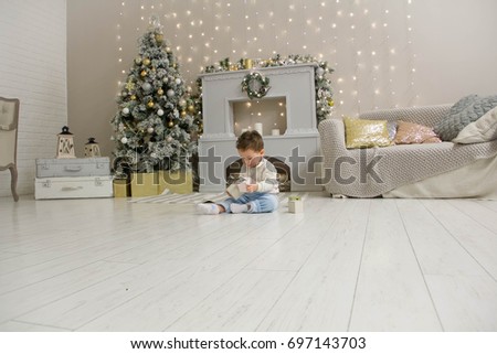 Cute toddler playing with his Christmas present in the decorated room. wooden toy. Family Xmas morning in decorated living room with kids gifts, fireplace Christmas tree.