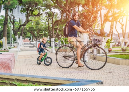 Happy family is riding bikes outdoors and smiling. Father on a bike and son on a balancebike.