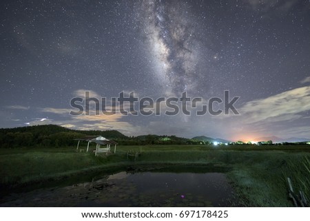 cottage in green fields and milky way