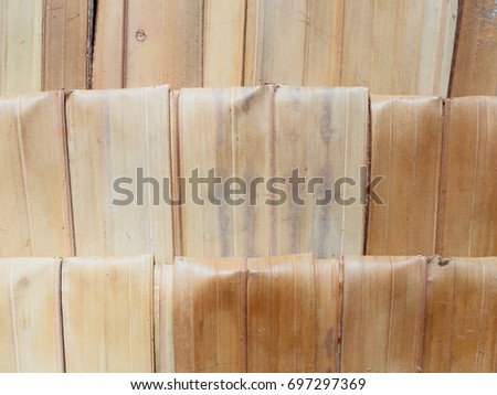 Close up shot of pile of white and brown folded dry sugar palm leaf used for making wall or roof of shelter, and also be used as background and organic texture