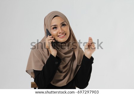 Beautiful Muslim young woman wear Hijab with happy face make a call using her mobile phone