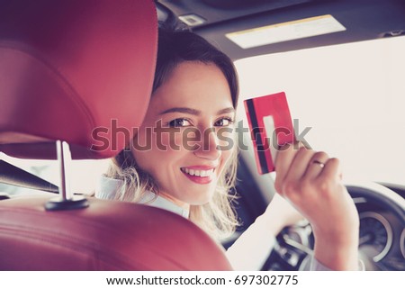 Happy woman sitting inside her new car showing credit card  Royalty-Free Stock Photo #697302775
