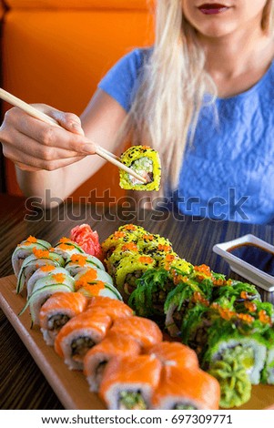 Woman eats traditional sushi rolls at the restaurant - close up photo.