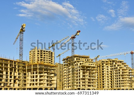 Tower cranes against the building under construction Royalty-Free Stock Photo #697311349