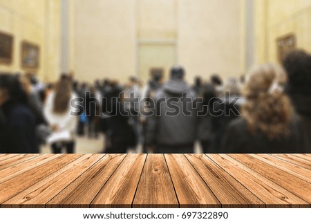 Empty wooden board table in front of blurred background. Perspective of crowd of people at gallery exhibition or in a museum can be used for display a products or advertise text