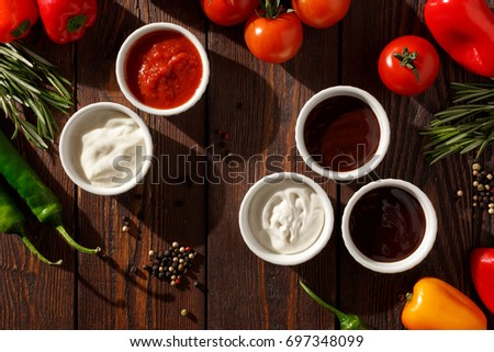 Sauces and vegetables on a wooden table, morning, dawn. Tomato, barbecue, cheese, garlic, mayonnaise, adzhika, teriyaki. Pizza sauces.
