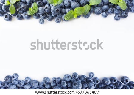 Ripe blueberries and mint on white background. Berries at border of image with copy space for text. Background berries. Top view. 