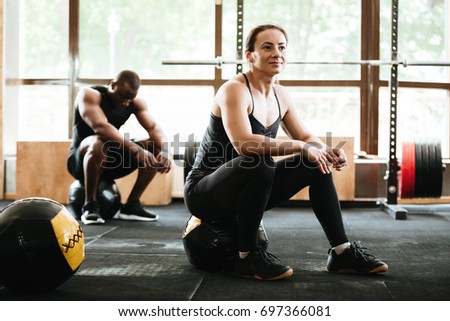 Picture of group of multiethnic sports strong people make sport exercises with ball in gym.