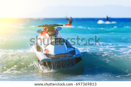 modern jet sways in the surf near shore on background of mountains in Greece Royalty-Free Stock Photo #697369813