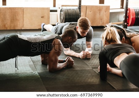 Picture of group of multiethnic sports strong people make sport exercises in gym.