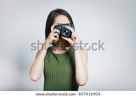 Beautiful young woman photographing on retro camera isolated on gray background