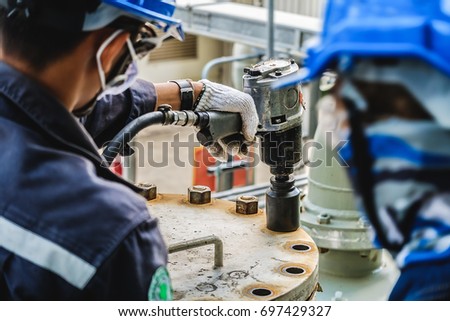 Workers hand holding machine tightening  nut, The mechanic is repairing the machine in the factory, Maintenance team in industrial plant Royalty-Free Stock Photo #697429327