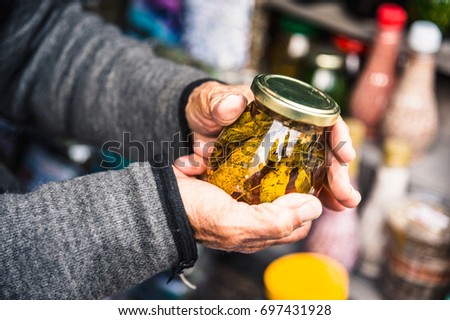Old wrinkled hands hold a jar with mountain jam from the leaves of Caucasian trees