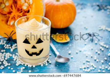 Funny treats for kids for Halloween pumpkin cream in a cute decorated glass