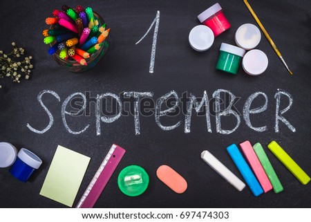 The inscription is September 1. Surrounded by chalk and school supplies on a black board