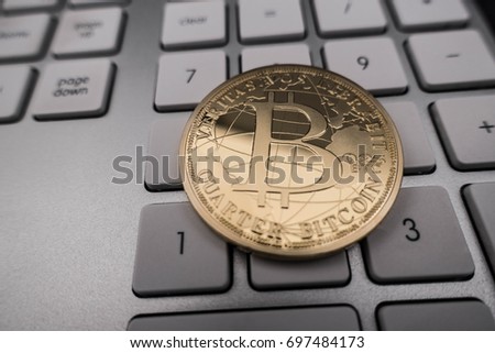Golden coin of bitcoins on computer keyboard