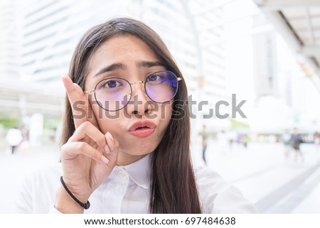 Pretty business woman take a self portrait with her smart phone outside, Asian nerdy glasses girl selfie over building background