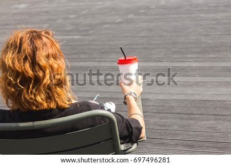 Red-haired girl with a paper cup in her hand