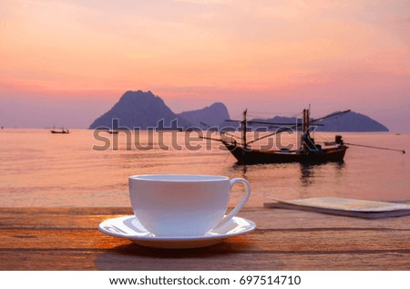 a selective focus picture of a cup of coffee on wooden table in the morning sunrise 