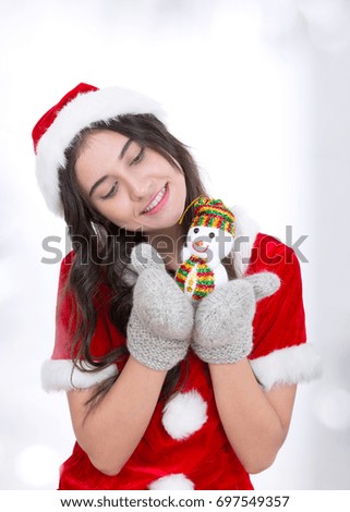 Young girl celebrating xmas playing with snowman on hand. Tree on a background. Holidays, winter and celebration concept.