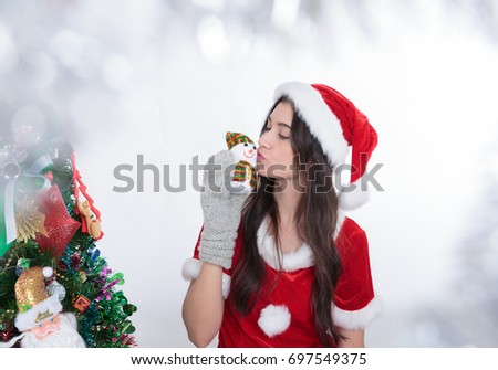 Young girl celebrating xmas kiss snowman on hand. Tree on a background. Holidays, winter and celebration concept.