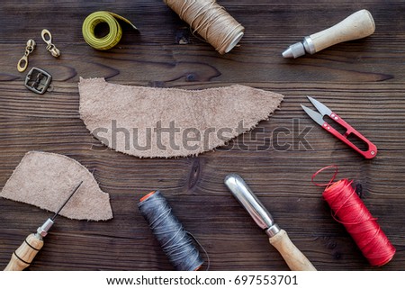 Leather craft accessories. Tools on dark wooden background top view