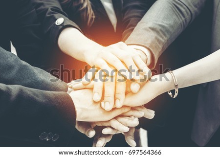 Image of businesspeople hands on top of each other as symbol of their partnership.