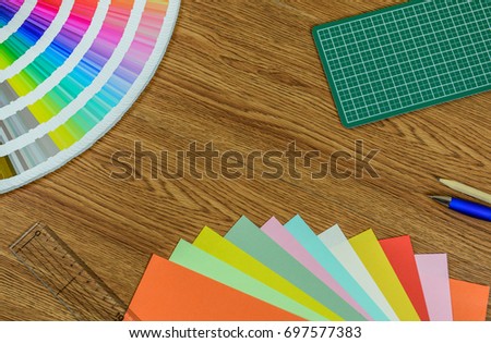 Colorful paper, cutting mat, swatch book and pencil on wooden table
