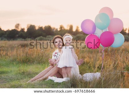 happy mother and daughter with balloons outdoor