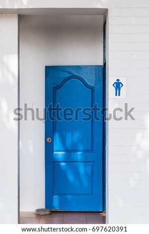 Public toilet with the blue wooden door is opened for the people in the urban park.