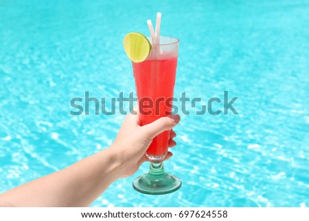 Hand of woman with glass of cocktail at resort