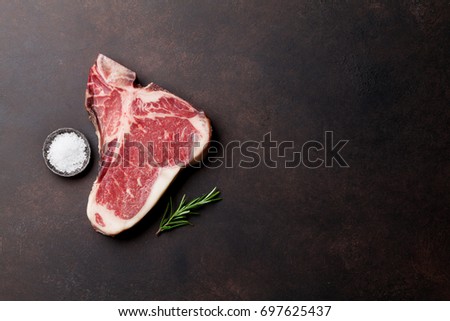 Raw T-bone steak cooking on stone table. Top view with copy space Royalty-Free Stock Photo #697625437