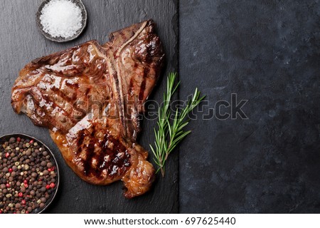 Grilled T-bone steak on stone table. Top view with copy space Royalty-Free Stock Photo #697625440