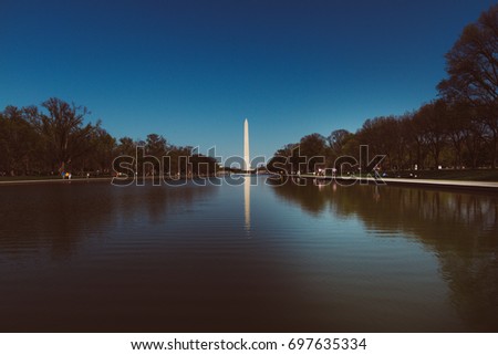 Washington DC tourism. Washington monument and memorial park. Blue Skies. Blue pond. Reflections in the pond. Historic skyline and landmark.